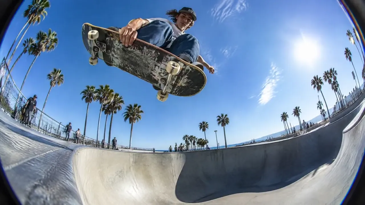 Skateboarder flying over a skate bowl through a fisheye lens