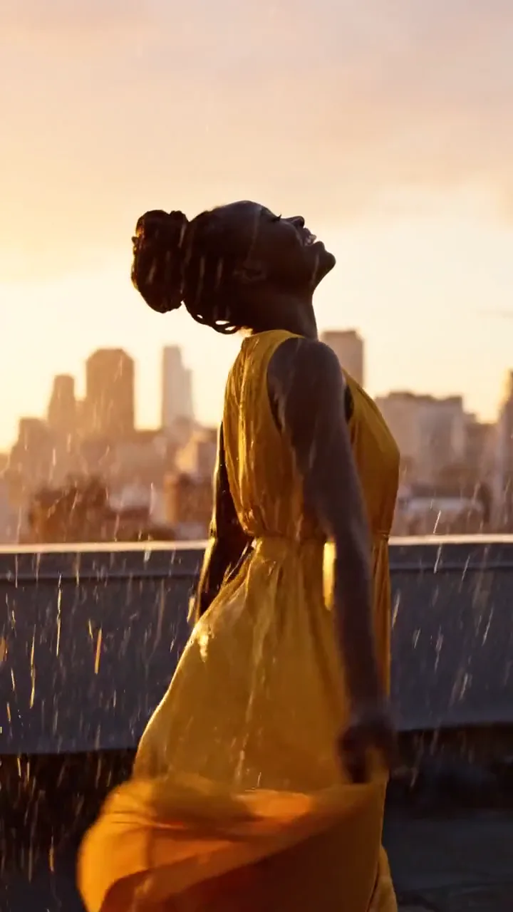Woman dancing in the rain on a rooftop at sunset